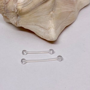 May include: Two clear plastic barbell body jewelry pieces with rounded ends.