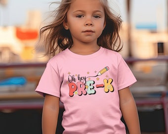 May include: A pink t-shirt with a colorful graphic that says "Oh hey PRE-K" with a yellow pencil and stars.