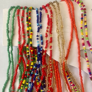 May include: A collection of colorful beaded necklaces in various patterns and colors, including green, red, yellow, blue, black, and white.