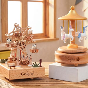 K&ouml;nnte beinhalten: Holz-Spieluhren. Eine ist ein Riesenrad mit Tierfiguren, die andere ein Karussell mit Einh&ouml;rnern. Das Riesenrad tr&auml;gt den Namen "Carly" und ein Wolkensymbol. Das Karussell tr&auml;gt den Namen "Daylen" und einen Pfotenabdruck.