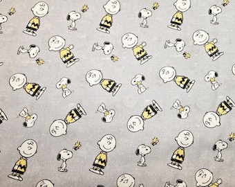 May include: A grey fabric with a repeating pattern of cartoon characters. The characters are all wearing yellow shirts and have black hair. The background is a light grey.