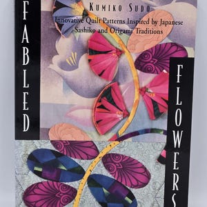 May include: A book cover titled "Fabled Flowers" featuring a floral design with pink, blue, and orange accents. The book is by Kumiko Sudo and focuses on innovative quilt patterns inspired by Japanese Sashiko and Origami traditions.