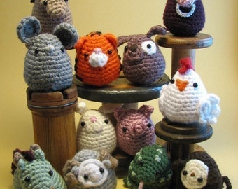 May include: A collection of 12 crocheted animal plushies, including a horse, a mouse, a tiger, a dog, a chicken, a rabbit, a pig, a frog, a sheep, a monkey, and a cow. The plushies are arranged on a wooden shelf and are all different colors and sizes.