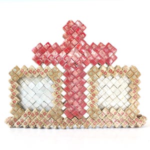 May include: A red cross made of small squares is centred on top of a larger rectangular structure made of smaller squares. The squares are all the same size and are arranged in a grid pattern. The squares are a mix of red, white and gold.