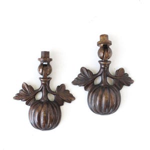 May include: Two matching bronze-toned metal drawer pulls featuring a central pumpkin-shaped body with ribbed detailing and two symmetrical leaf-shaped accents on either side. Each pull has a hinged top connector with a cylindrical mounting post.