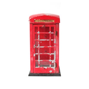 May include: A miniature red telephone booth with the word "TELEPHONE" above the door. The booth has a distressed, weathered appearance with visible paint chipping. The base is black.