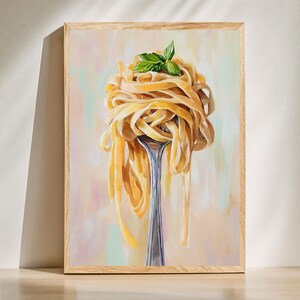 May include: A framed art print featuring a fork holding a portion of pasta. The pasta is a light yellow color, with a few green basil leaves on top. The background has soft pastel colors.