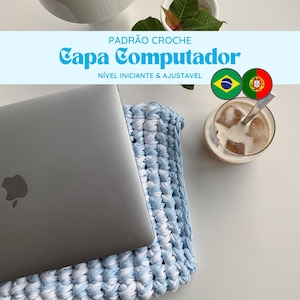 Może przedstawiać: Niebieska i biała dzianinowa osłonka na laptopa z laptopem na górze. Tekst "PADRAO CROCHE Capa Computador NIVEL INICIANTE & AJUSTAVEL" znajduje się na niebieskim banerze nad osłonką. Brazylijskie i portugalskie flagi znajdują się po prawej stronie banera.