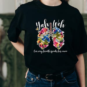 May include: Black t-shirt with a white graphic of a pair of lungs with flowers and the text "Yah Weh" and "Our very breath speaks his name".