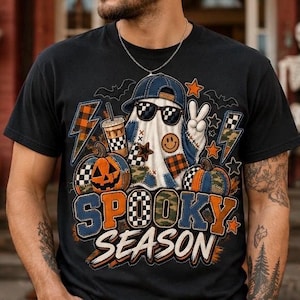 Puede incluir: Una camiseta negra con un gráfico de un fantasma con gorra de béisbol azul y gafas de sol, sosteniendo un café y haciendo el signo de la paz. El diseño incluye calabazas, rayos, estrellas, murciélagos y el texto SPOOKY SEASON.