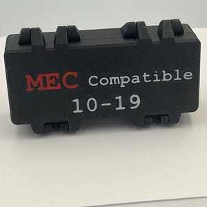 May include: A rectangular black plastic storage case with a hinged lid and two latch closures. The front of the case features the text MEC Compatible in red and white lettering, with the white numerical text 10-19 printed directly below it.