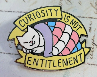 May include: Enamel pin featuring a sleeping white cat under a blanket in the colors of the transgender flag. The pin has a yellow banner with the text "CURIOSITY IS NOT ENTITLEMENT" in black letters, with a black border.