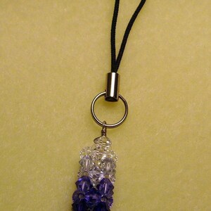 Peut inclure: Un porte-cl&eacute;s ou breloque de t&eacute;l&eacute;phone orn&eacute; de perles d&eacute;grad&eacute;es transparentes, violettes et violet fonc&eacute;. Il comporte une boucle en cordon noir, un anneau argent&eacute; et un tube en m&eacute;tal argent&eacute;.
