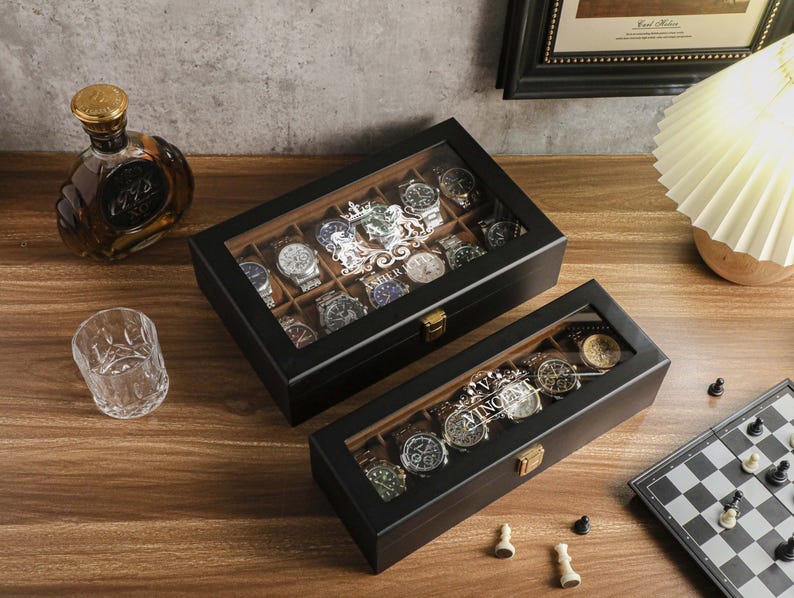 May include: Two black wooden watch display cases with glass tops, filled with various wristwatches. A bottle of liquor, a drinking glass, and a chessboard are also on the wooden surface.