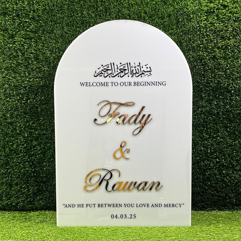 Puede incluir: Un cartel blanco en forma de arco con letras doradas. El cartel dice "بسم الله الرحمن الرحيم"  "WELCOME TO OUR BEGINNING" "Fady & Rawan" "AND HE PUT BETWEEN YOU LOVE AND MERCY" "04.03.25".