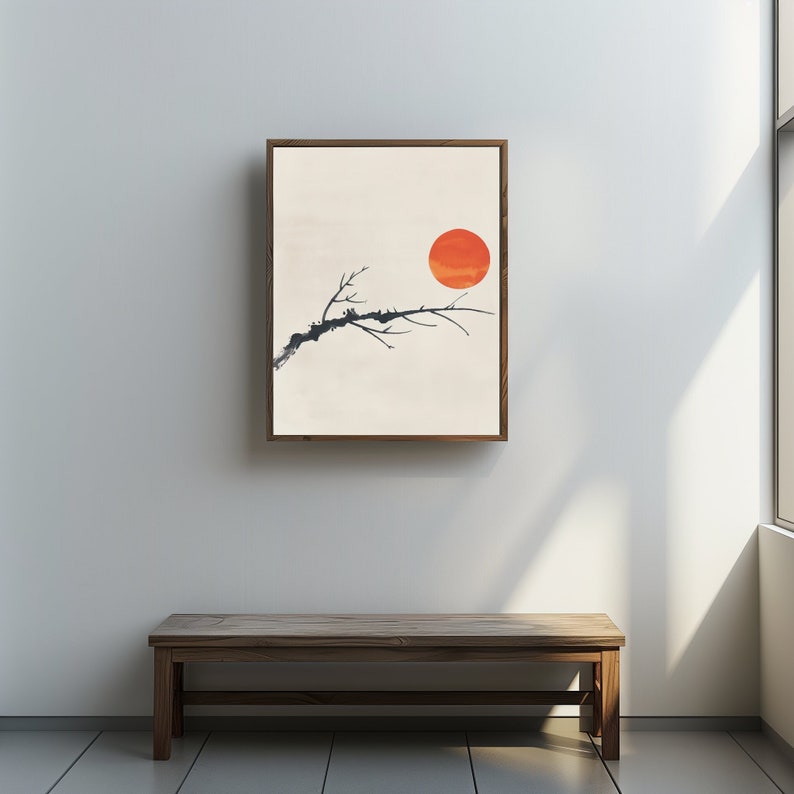 May include: A framed print of a minimalist watercolor painting depicting a single branch of a tree with a large orange sun in the background.