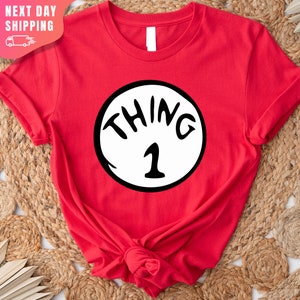May include: Red t-shirt with a white circle and the text "THING 1" in black.