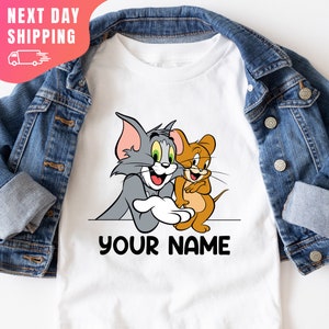 May include: White t-shirt featuring Tom and Jerry cartoon characters. The text "YOUR NAME" is printed below the characters.
