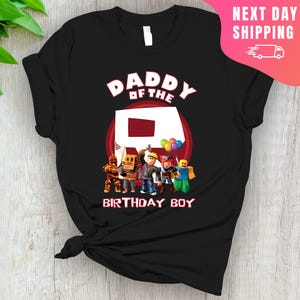May include: Black t-shirt with a red circle and the text "Daddy of the R Birthday Boy". Inside the circle is a red letter R. There are five cartoon characters standing in front of the letter R.