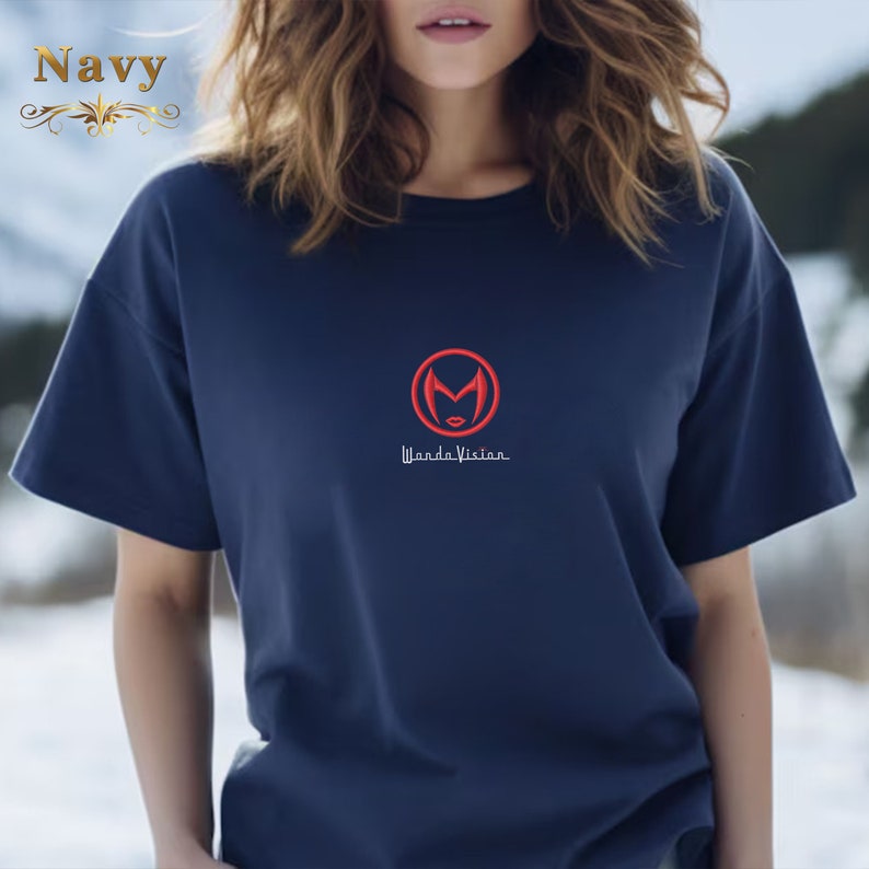 May include: A navy blue t-shirt with a red circle containing a stylised letter "M" and a red female face. The text "Wanda Vision" is printed below the circle.