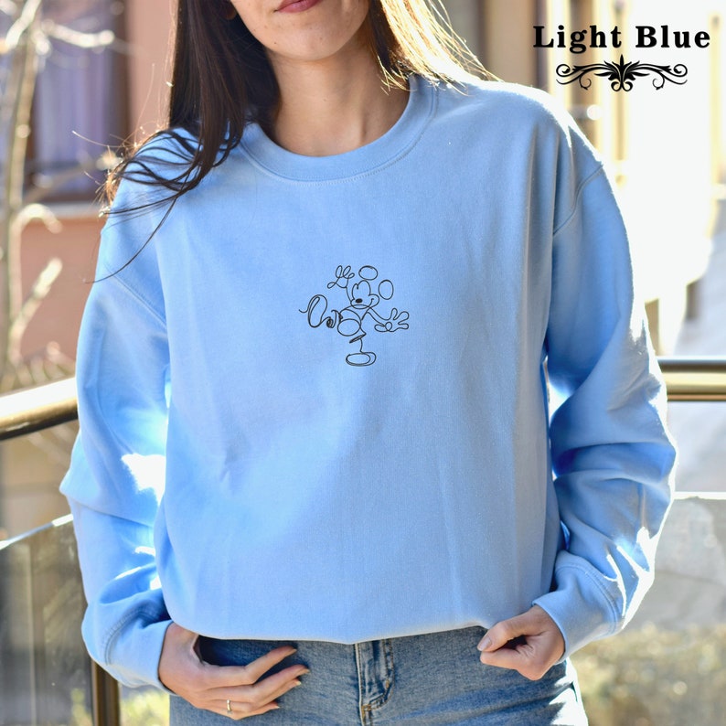 May include: Light blue sweatshirt with a black line drawing of Mickey Mouse on the front.