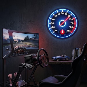 Puede incluir: Una configuración de juego con un monitor curvo que muestra un juego de carreras de coches, un volante y un asiento de carreras. Un velocímetro de neón azul está montado en la pared. Un coche de modelo está en una estantería de madera. La escena está iluminada con luces azules y rojas.