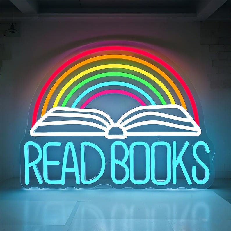 May include: A neon sign with a rainbow arching over an open book. The words "READ BOOKS" are in bright blue neon. The rainbow features red, orange, yellow, green, and blue colors.