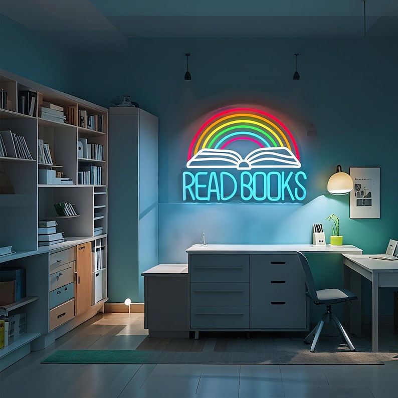 May include: A neon sign in a room with the words "READ BOOKS" in bright blue letters. The sign features a rainbow arching over an open book. The room has bookshelves, a desk, and a chair.