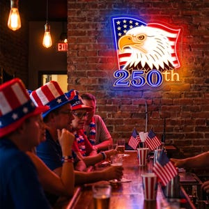 May include: A neon sign with a patriotic theme, featuring a bald eagle and the text "250th" against a brick wall. People wearing patriotic hats and holding drinks are seated at a bar, with small American flags on the counter.