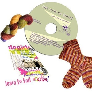 May include: A DVD titled "The Zen of Socks" with a serene path for knitting socks. The DVD is accompanied by a skein of yarn in shades of orange, green, and red, a pamphlet titled "alogirls" with a hand-knitted sock design, and a pair of striped socks in shades of orange, red, and purple.