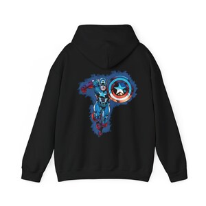 May include: Black hooded sweatshirt featuring a Captain America graphic on the back. The graphic depicts Captain America in a dynamic pose, holding his shield. The shield is red, white, and blue with a star. The sweatshirt is made of a soft material.