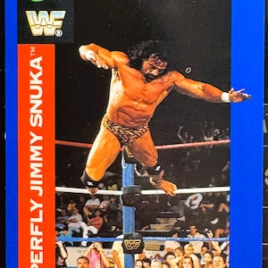 May include: A wrestling trading card showing "Superfly" Jimmy Snuka mid-air. The card has a blue border and a red stripe with the wrestler's name. The WWF logo and "Classic" are visible.