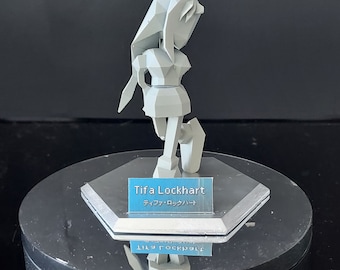 Könnte beinhalten: Eine weiße, niedrig-polygonal Figur einer weiblichen Figur mit langen Haaren, die einen kurzen Rock und Stiefel trägt. Die Figur steht auf einem runden, silbernen Sockel mit einem blauen Namensschild, auf dem "Tifa Lockhart" und "ティファ・ロックハート" steht.