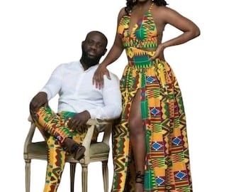 May include: A couple wearing matching outfits with a colorful geometric pattern. The woman is wearing a halter top and a long skirt with a slit. The man is wearing a white shirt and pants.