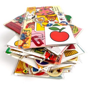 Puede incluir: Una colecci&oacute;n de pegatinas y ef&iacute;meras de papel vintage, que incluyen im&aacute;genes de un conejo, un oso de peluche, una manzana y un buf&oacute;n. Las pegatinas est&aacute;n en un embalaje de pl&aacute;stico transparente.