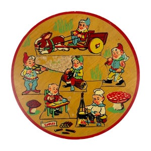 May include: A circular wooden puzzle featuring colorful illustrations of gnomes in various activities, including a gnome driving a rabbit-drawn cart, playing a violin, sitting on a log, carrying an axe, eating, and cooking over a fire. The word SIMPLEX is printed.