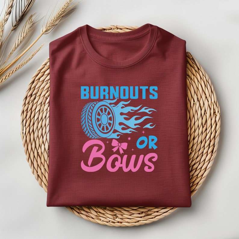 May include: A maroon t-shirt with the text "Burnouts or Bows" in blue and pink. The text is accompanied by a blue tire with flames and a pink bow.