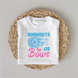 May include: White t-shirt with a blue tire and flames graphic and the text "Burnouts or Bows" in pink and blue.