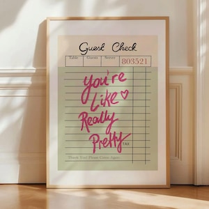 May include: A framed print of a guest check with the text "you're like really pretty" written in pink cursive. The check has the words "Guest Check", "Table", "Guests", "Server", and "803521" printed on it.