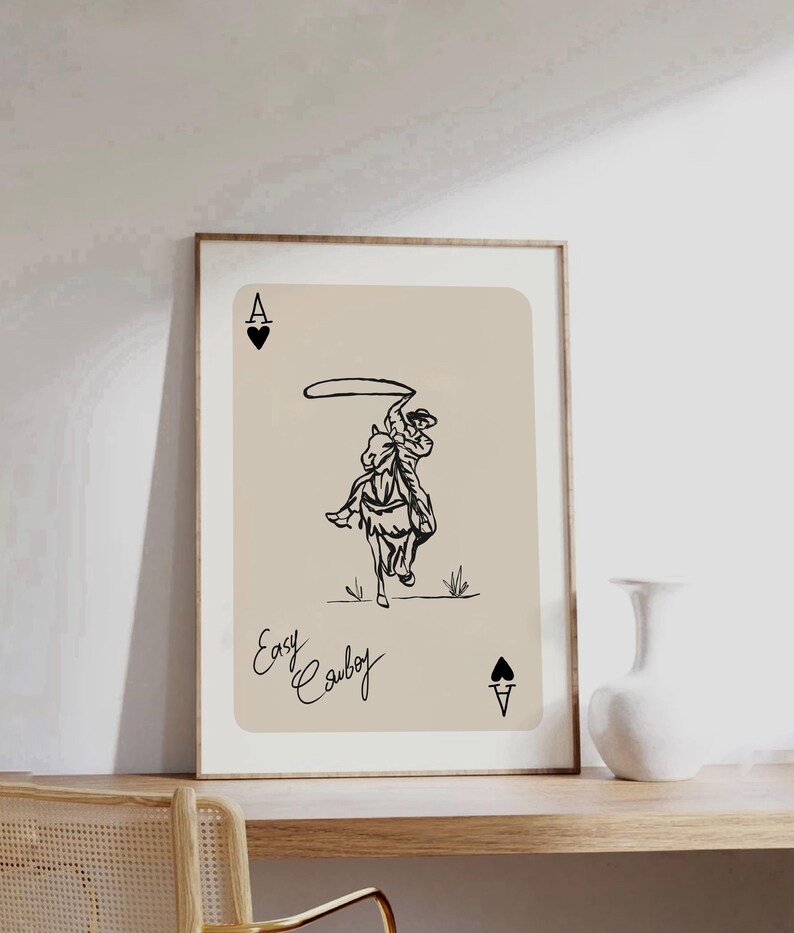 May include: A black and white illustration of a cowboy riding a horse and lassoing. The image is on a beige background with the text "Easy Cowboy" and the Ace of Spades card symbol.