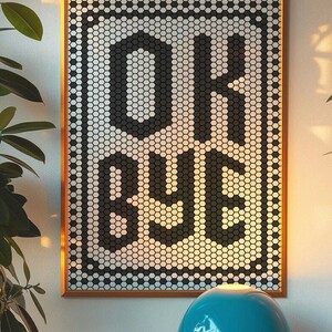 Peut inclure: Tableau encadré avec les mots "OK BYE" dans un motif en nid d'abeille noir et blanc. L'œuvre est dans un cadre en bois et est accrochée à un mur blanc. Une lampe bleue est au premier plan.