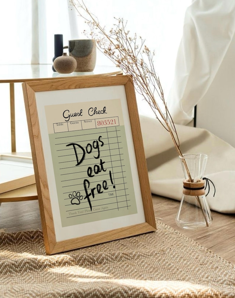 May include: A framed print with a wooden frame. The print is a guest check with the words "Dogs eat free!" written on it. The print also includes a paw print and the text "Thank You! Please Come Again."
