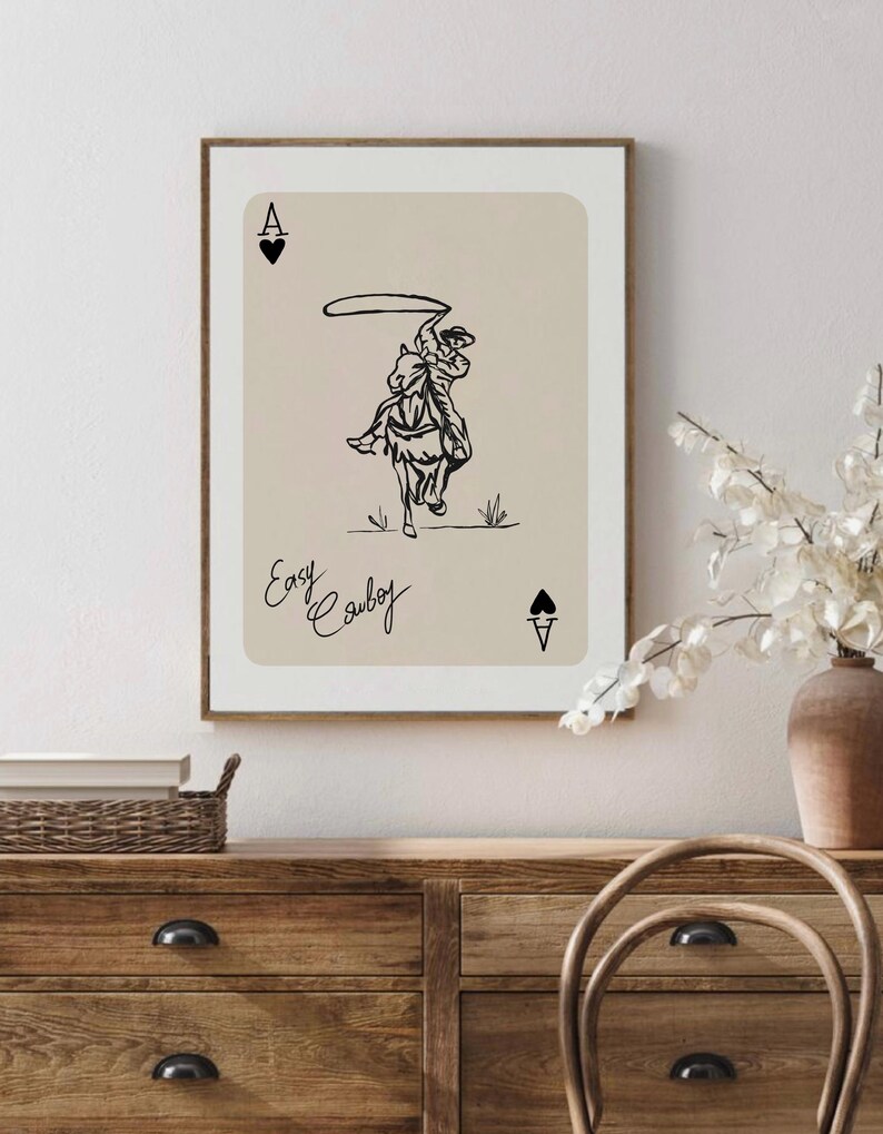 May include: A beige card with a black illustration of a cowboy riding a horse and lassoing. The card has the letter A and a spade symbol in the top left and bottom right corners. The text "Easy Cowboy" is written in cursive at the bottom of the card.