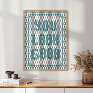 May include: A framed print with a white background and a teal blue honeycomb pattern that spells out the phrase "You Look Good".