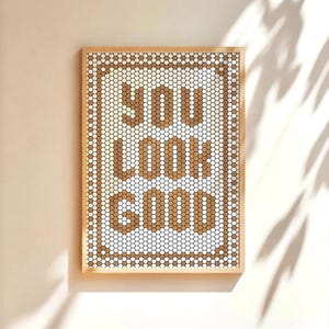 Könnte beinhalten: Ein gerahmtes Wandbild mit einem Mosaikdesign aus weißen und braunen Fliesen. Die Fliesen buchstabieren den Satz "You Look Good".