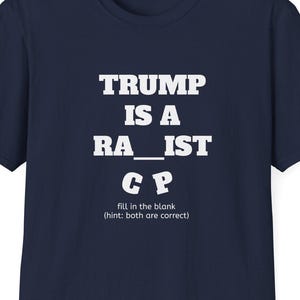 Może przedstawiać: Granatowa koszulka z białym napisem "TRUMP IS A RA_IST CP" z napisem "fill in the blank (hint: both are correct)". Koszulka ma okrągły dekolt.