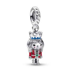 May include: Silver charm featuring a Nutcracker doll with a red and green uniform, blue crown, and pink cheeks. The charm has a silver loop for attaching to a bracelet or necklace.