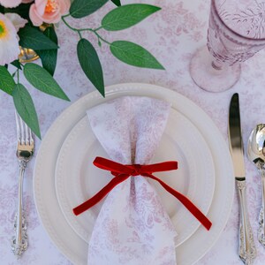 Thin, red, bow napkin rings in a Christmas table setting.