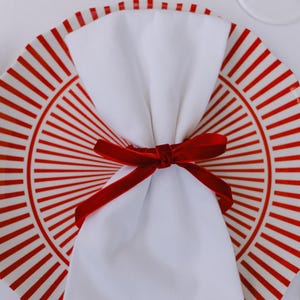 Thin, red, bow napkin rings in a Christmas table setting.