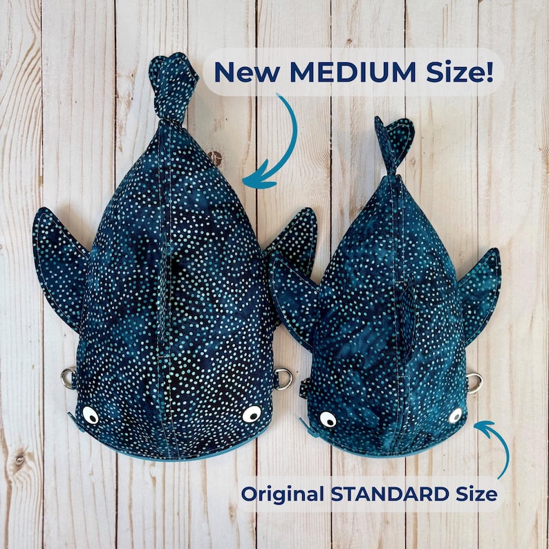 May include: Two shark-shaped plush toys in dark blue fabric with white polka dots. The larger toy is labelled "New MEDIUM Size!" and the smaller one "Original STANDARD Size." Both have white eyes and small metal rings.